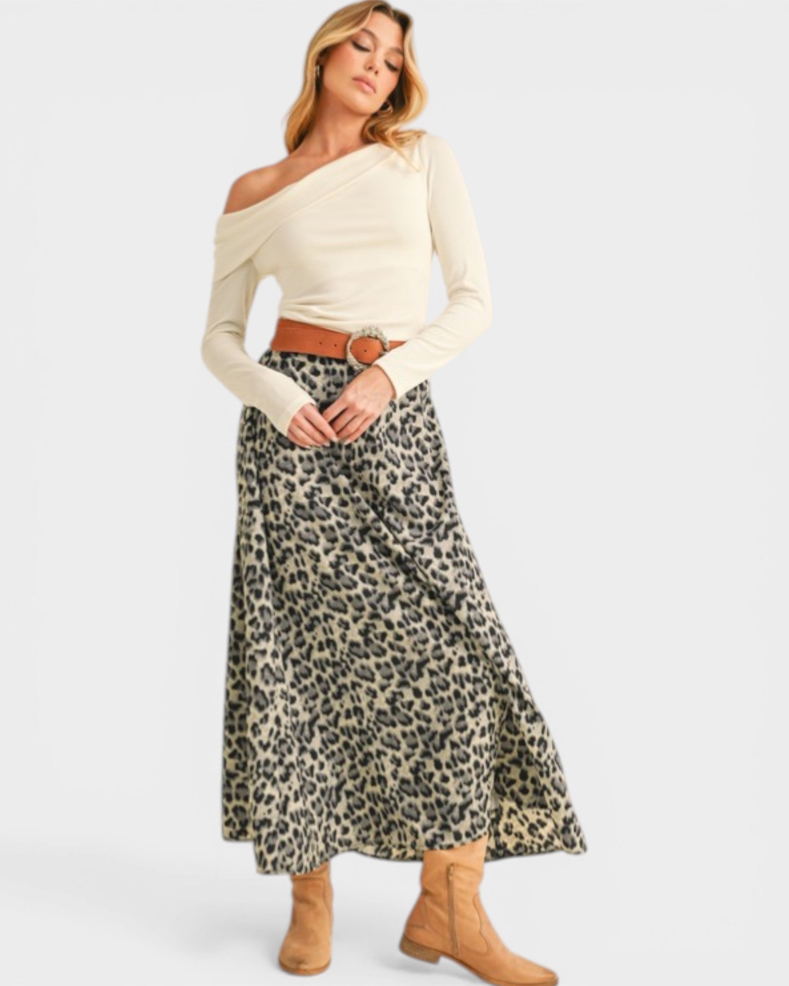 Woman wearing a cream off-shoulder top and leopard print skirt on a white background