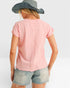 Person wearing a pink t-shirt and denim shorts with a wide-brimmed hat on a white background