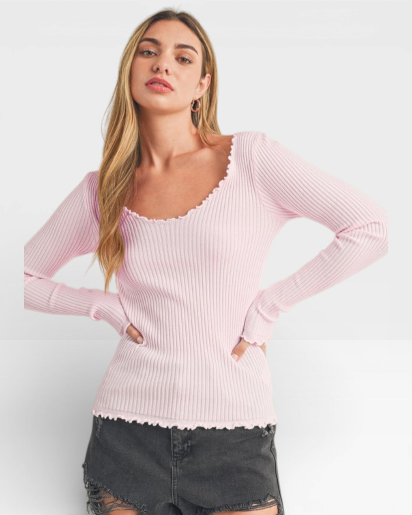 Woman wearing a pink ribbed sweater against a white background