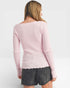 Person wearing a pink ribbed sweater and black shorts on a white background
