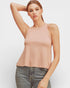 Woman wearing a light pink tank top and jeans on a white background