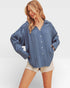 Woman wearing a blue denim shirt and white shorts on a plain background