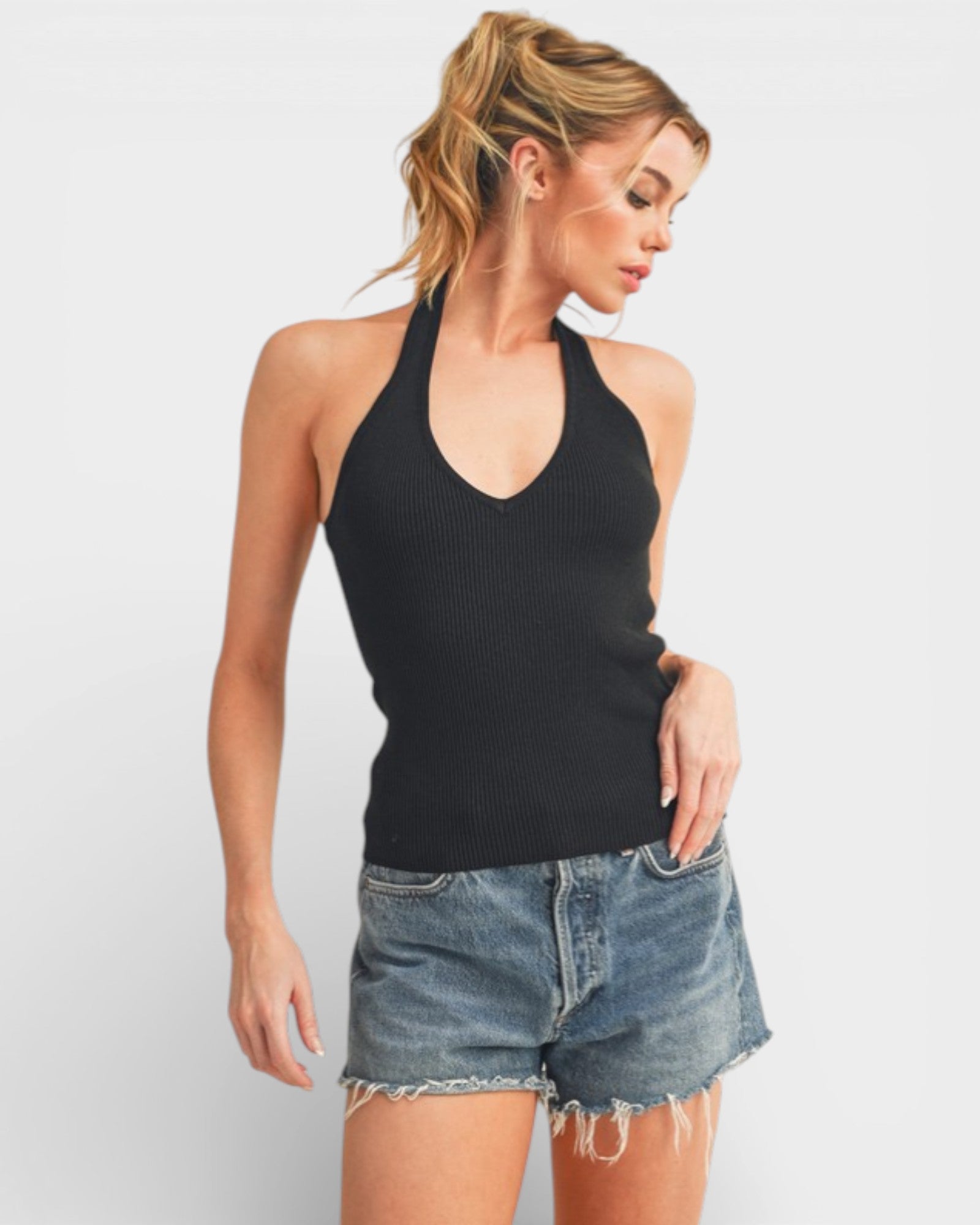 Woman wearing a black halter top and denim shorts on a white background