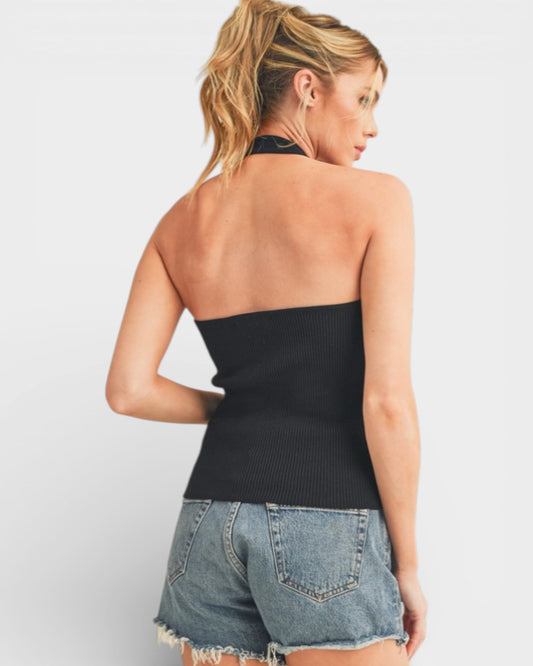Woman wearing a black halter top and denim shorts on a white background