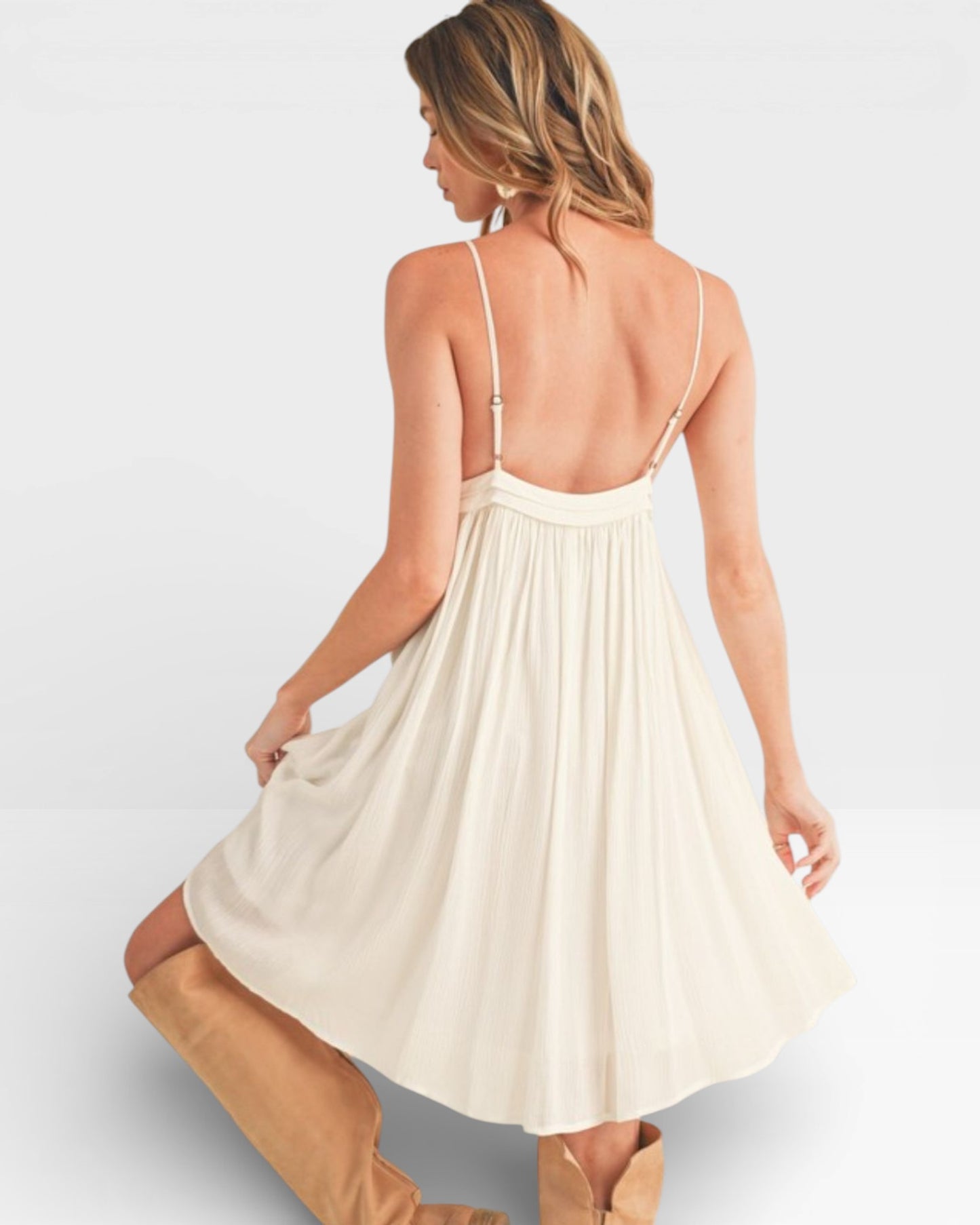 Woman wearing a cream-colored dress with thin straps on a light gray background