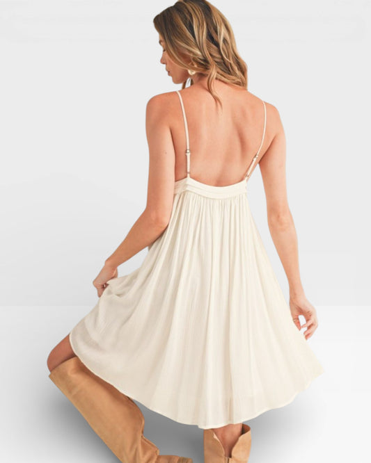 Woman wearing a cream-colored dress with thin straps on a light gray background