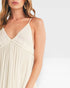 Woman wearing a beige dress with thin straps on a light gray background