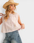 Woman wearing a straw hat, light pink top, and blue jeans on a white background