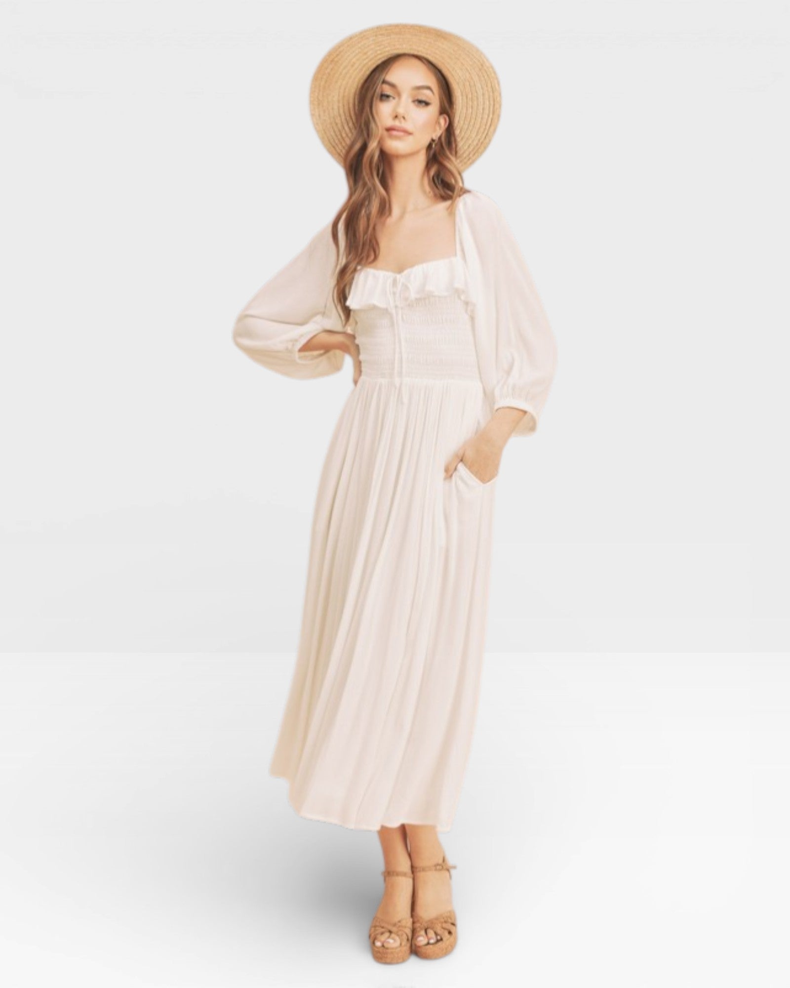 Woman wearing a white dress and straw hat on a plain background