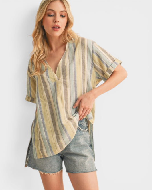 Woman wearing a striped shirt and denim shorts on a plain background