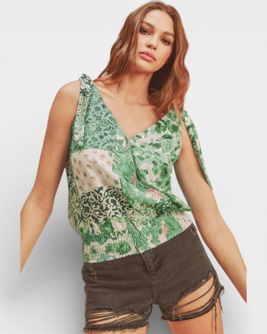 Woman wearing a floral top and ripped shorts on a plain background