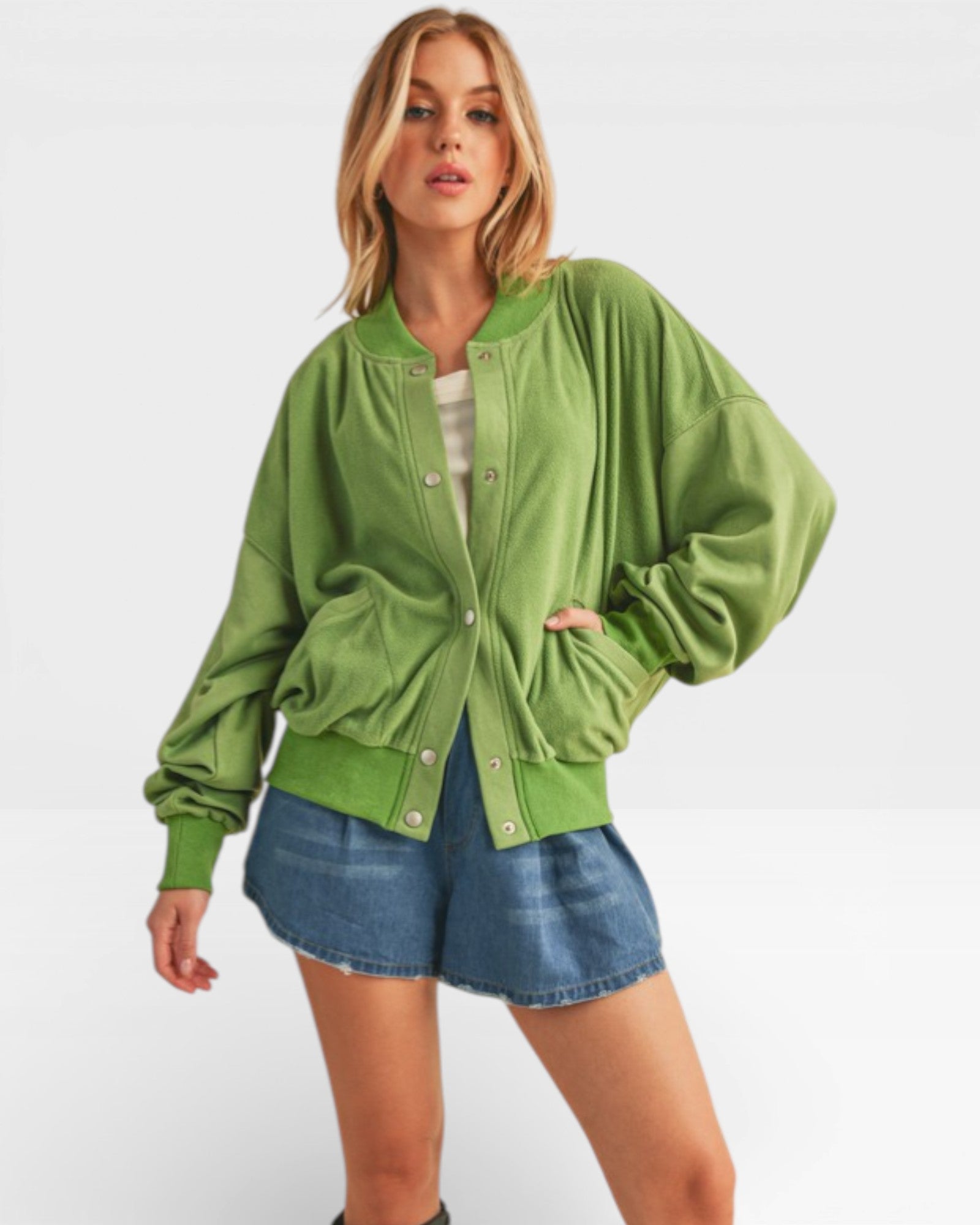 Woman wearing a green jacket and denim shorts on a white background
