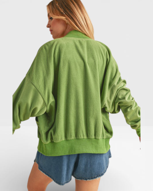 Person wearing a green oversized sweatshirt and denim shorts on a white background