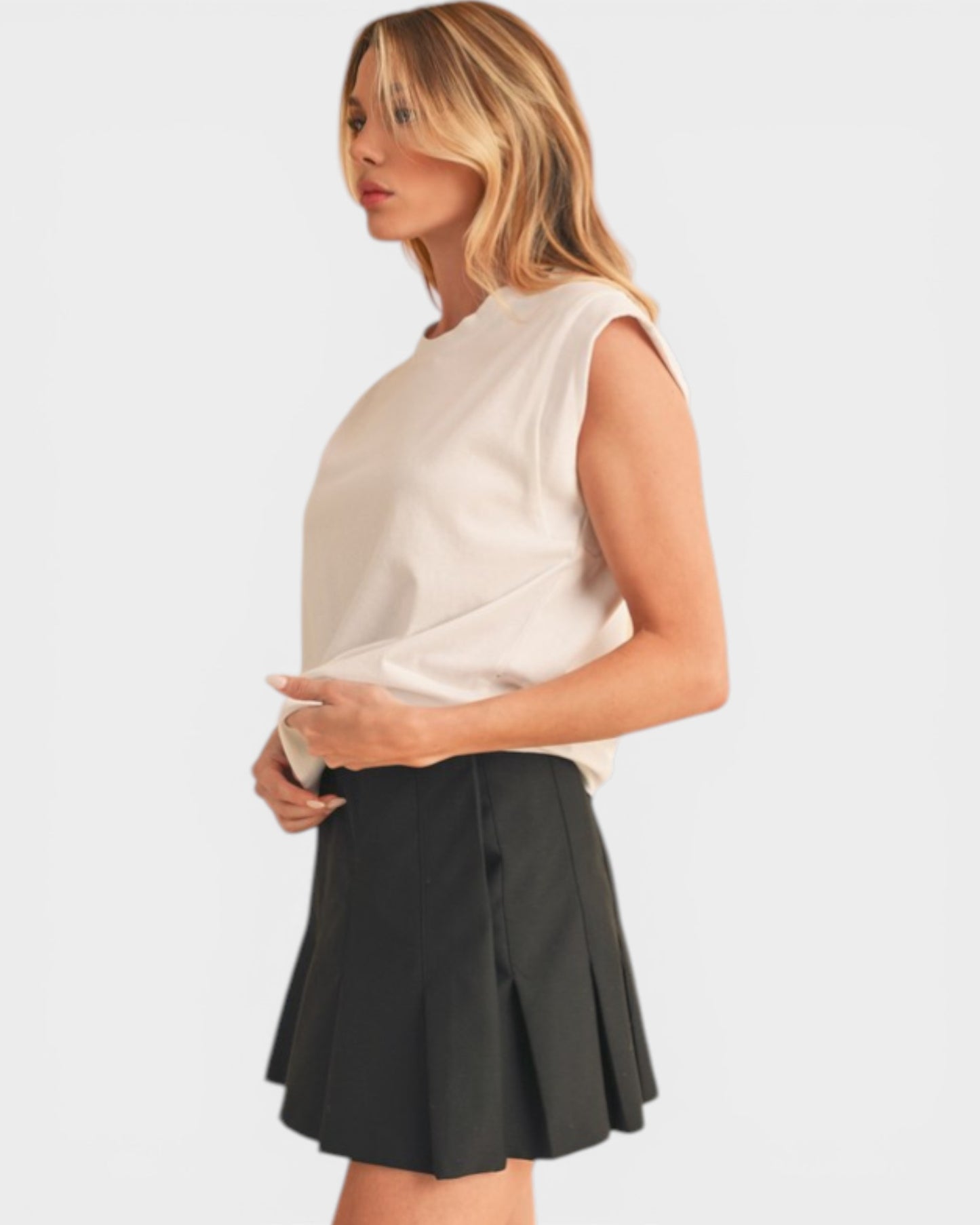 Woman wearing a white sleeveless top and black skirt on a light gray background