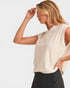 Woman wearing a beige sleeveless top and black pants on a light gray background
