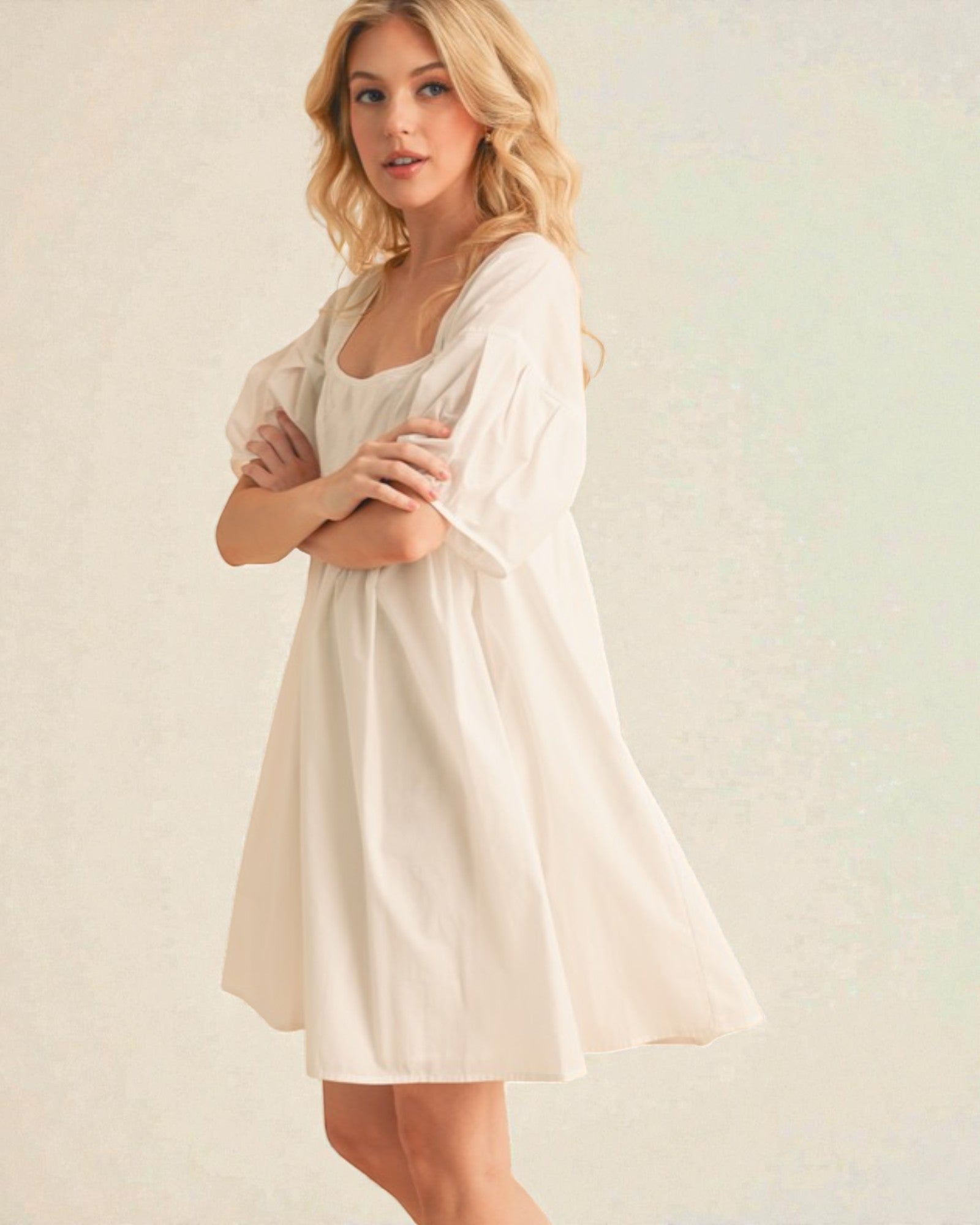 Woman wearing a light-colored dress against a plain background