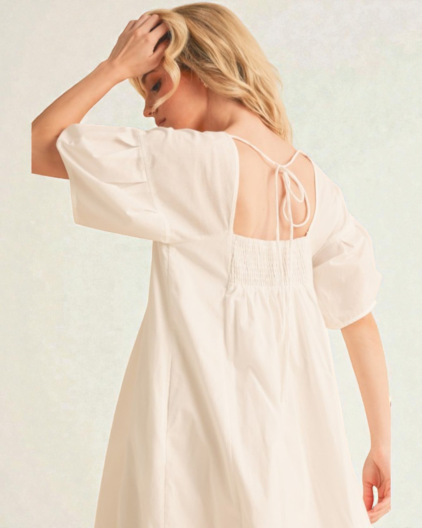 Woman wearing a light-colored dress with a plain background