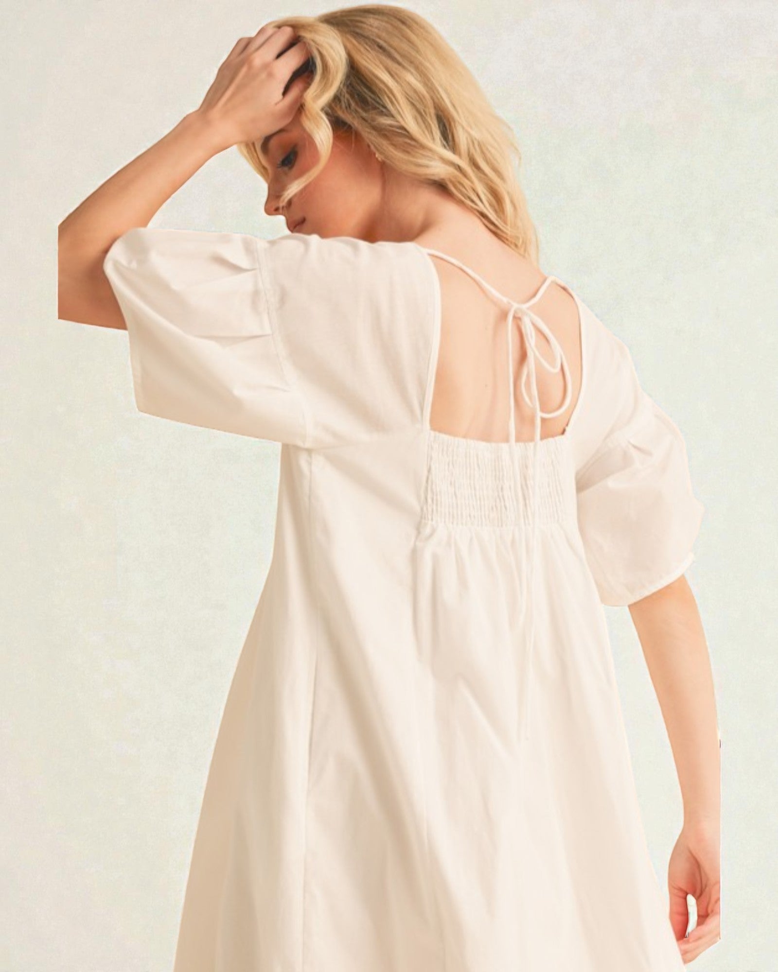 Woman wearing a light-colored dress with a plain background