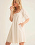 Woman wearing a white dress against a plain background