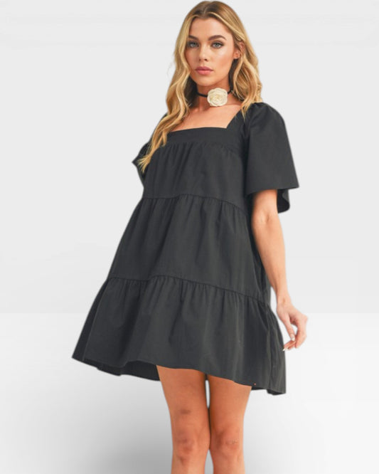 Woman wearing a black tiered dress on a white background