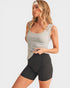 Woman wearing a gray tank top and black shorts on a white background