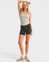 Woman wearing a light gray tank top and black shorts on a white background