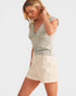 Woman wearing a light gray top and beige shorts on a white background