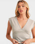 Woman wearing a light gray sleeveless top against a plain background