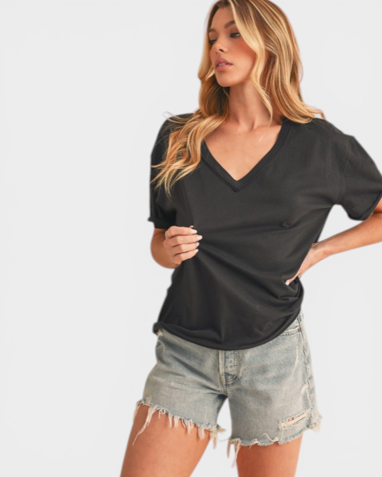 Woman wearing a black V-neck top and denim shorts on a white background