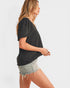 Woman wearing a black top and denim shorts on a white background