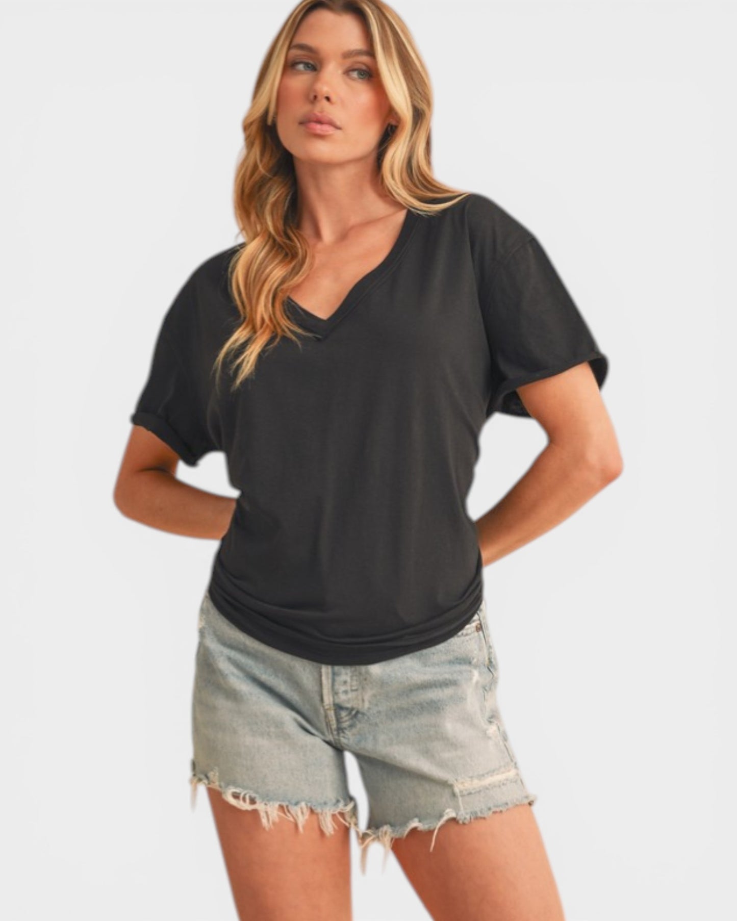 Woman wearing a black t-shirt and denim shorts on a plain background
