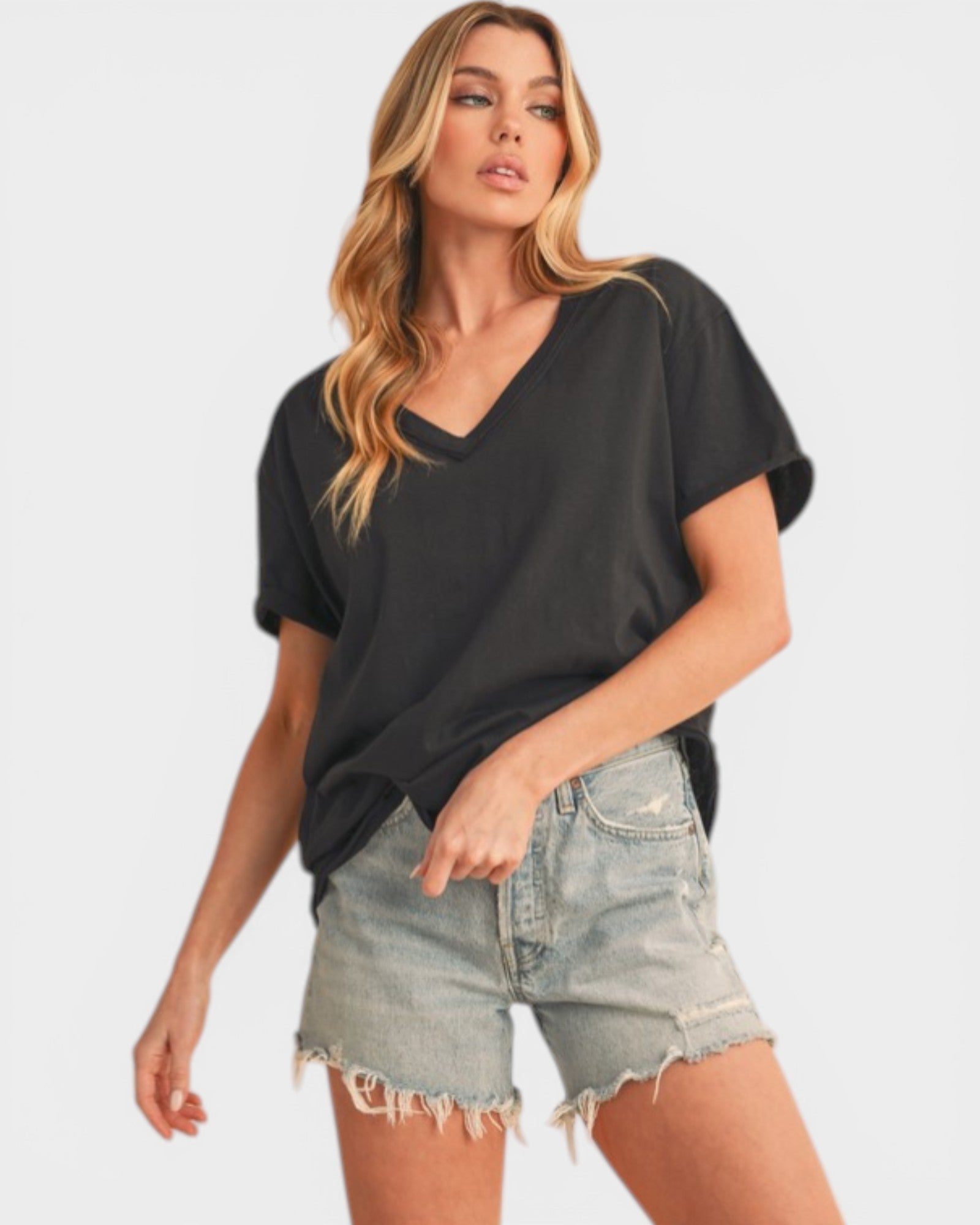 Woman wearing a black oversized t-shirt and denim shorts on a white background