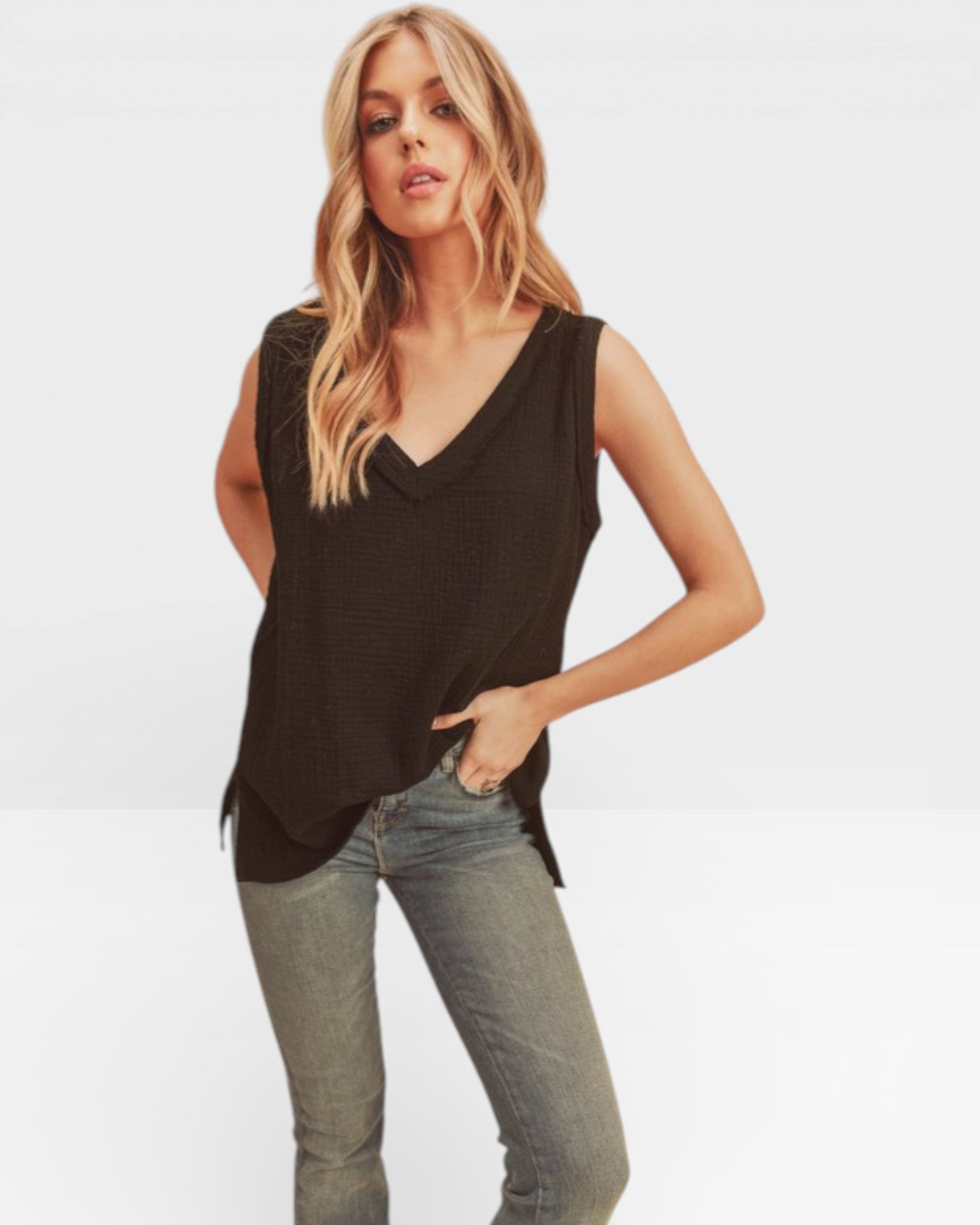 Woman wearing a black sleeveless top and light blue jeans on a white background