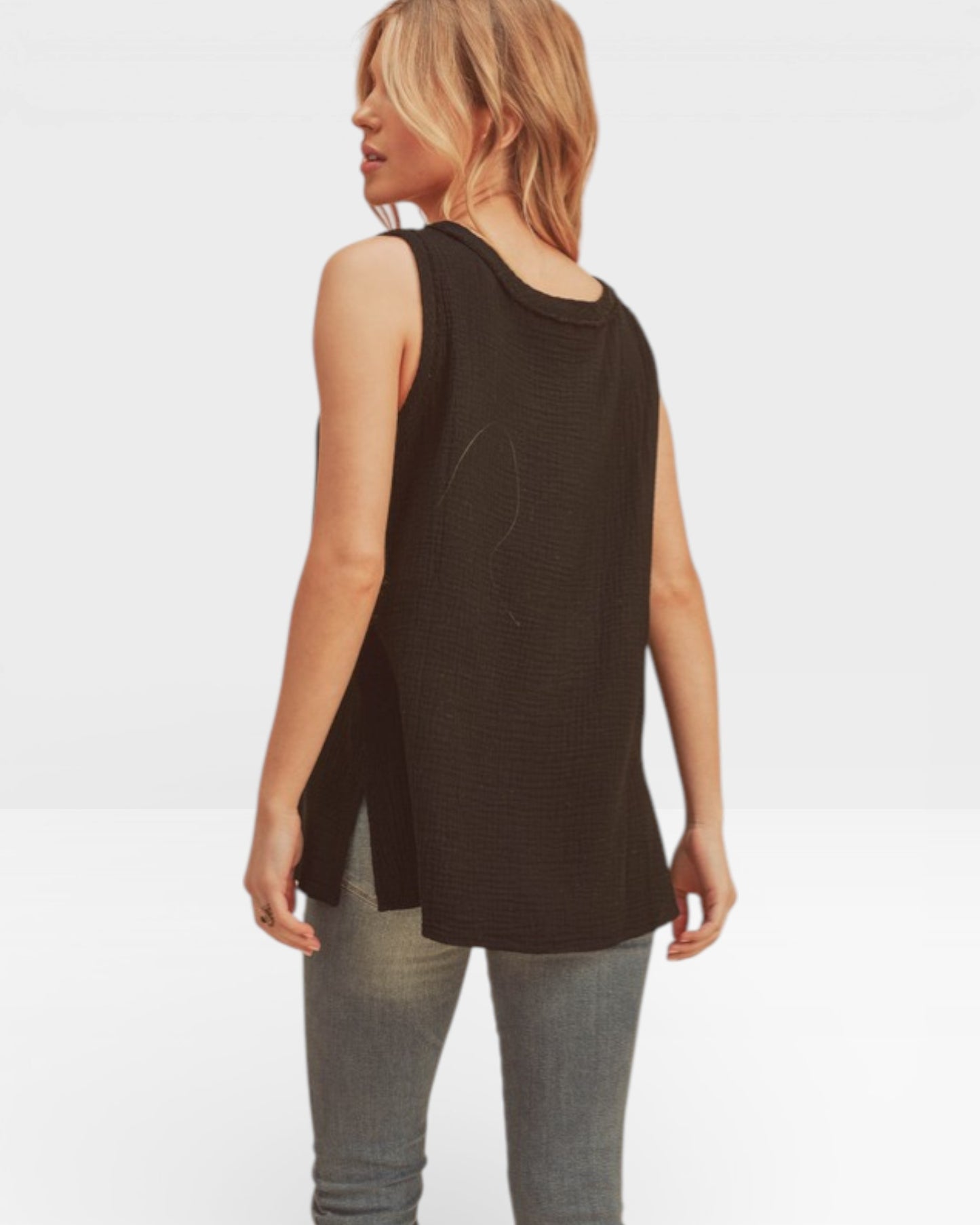 Woman wearing a black sleeveless top and gray pants on a white background