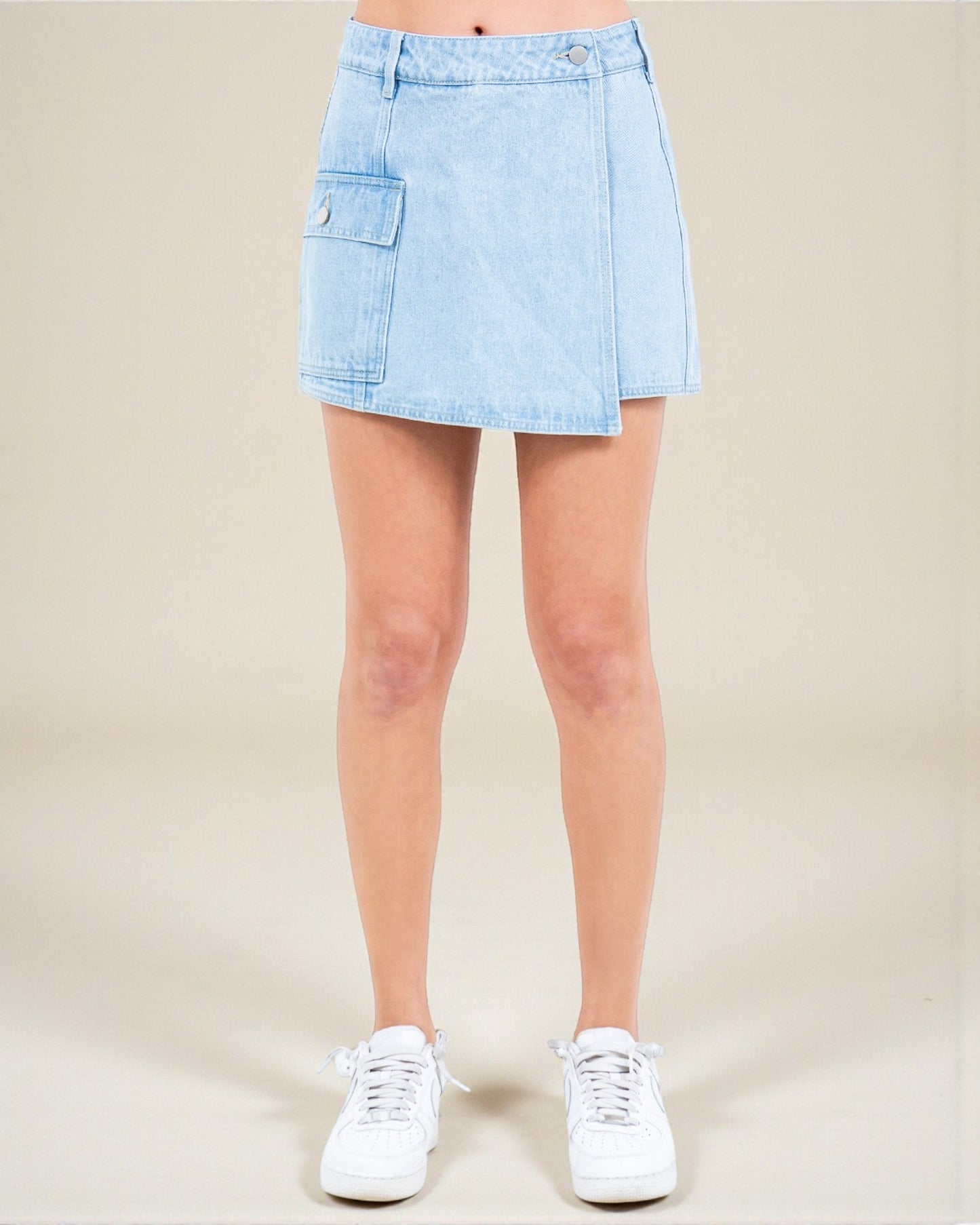 Light blue denim skirt worn by a person on a beige background