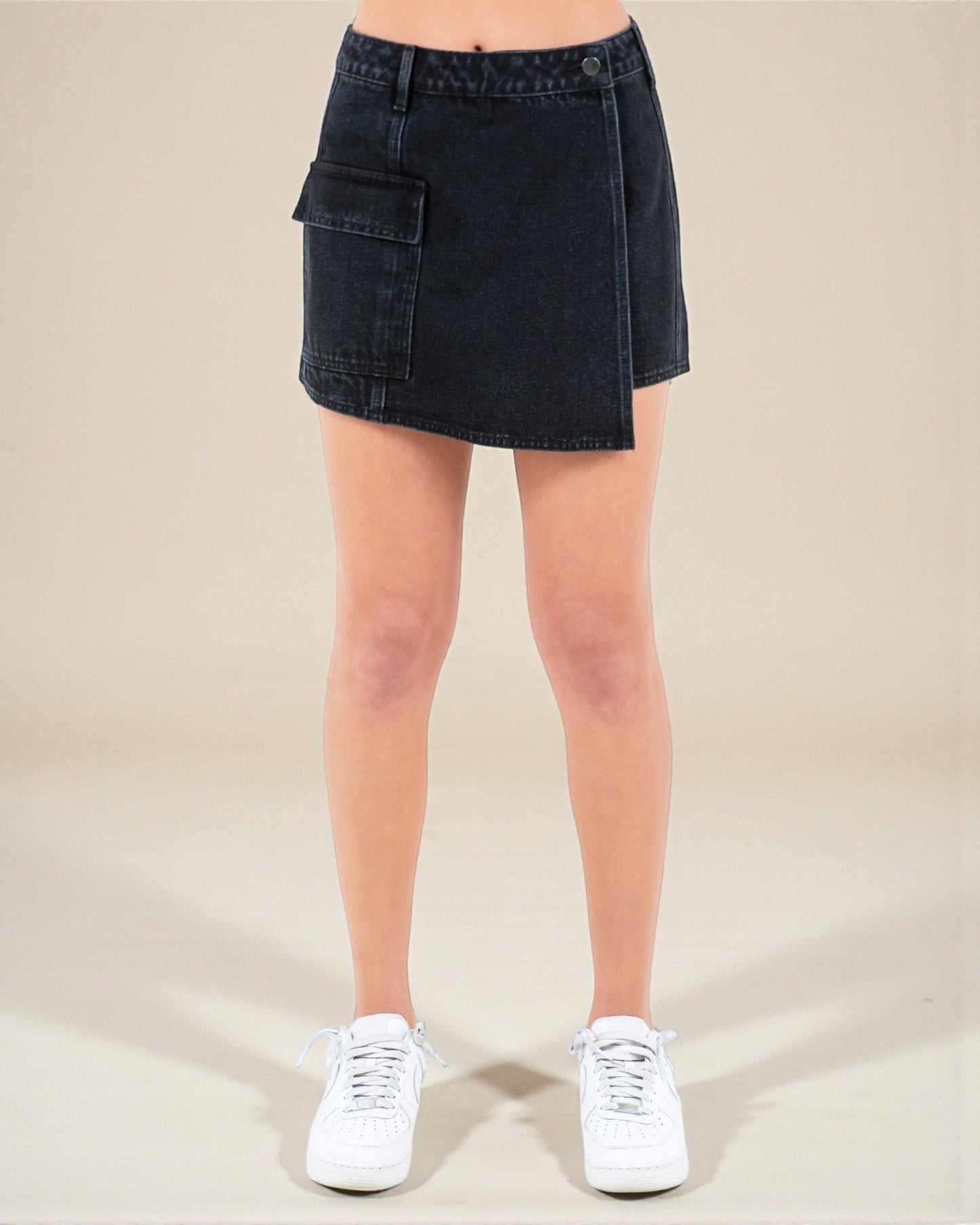 Black denim skirt worn by a person on a beige background