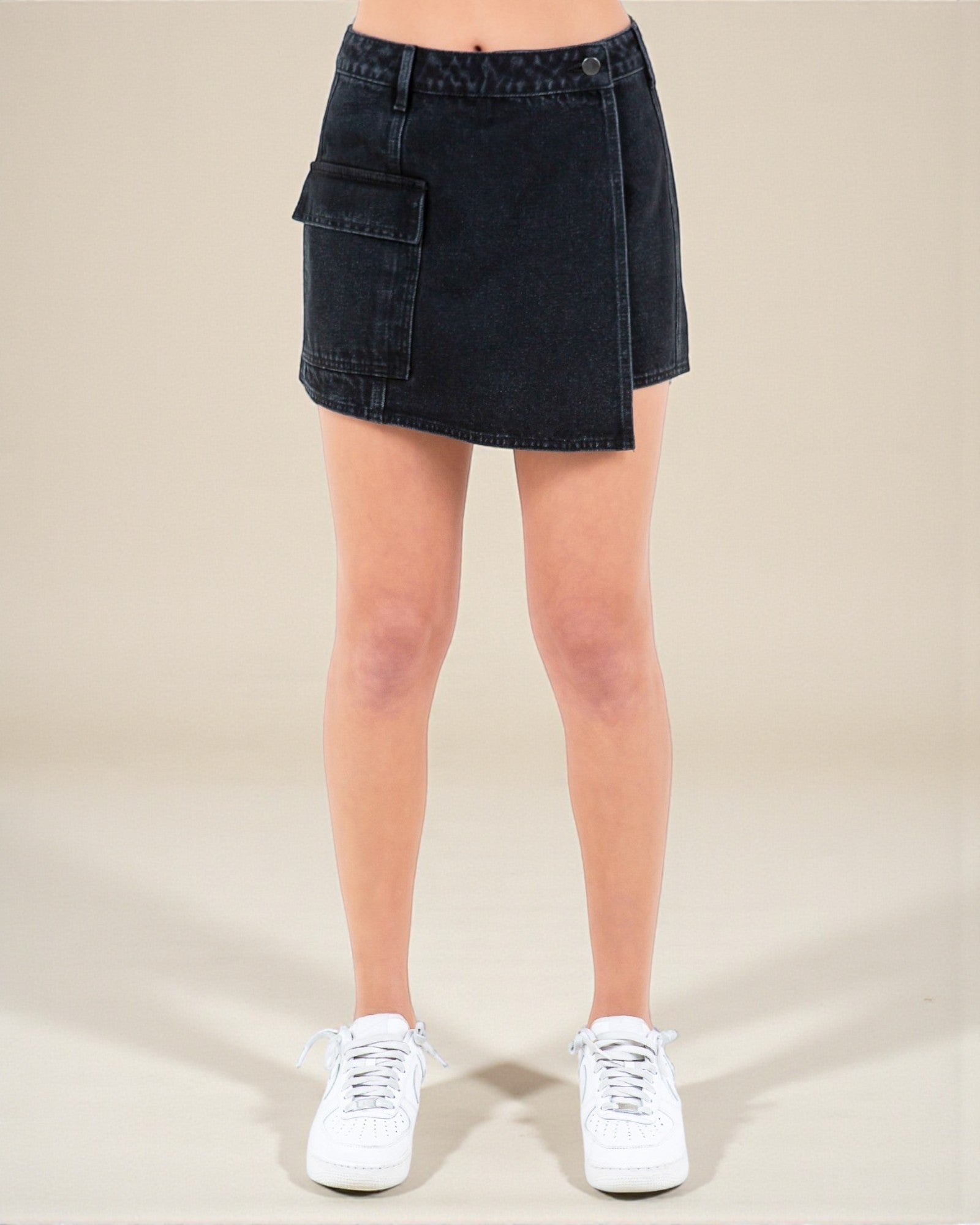 Black denim skirt worn by a person on a beige background