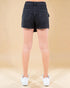 Person wearing black denim shorts on a beige background