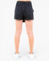 Rear view of a model wearing dark wash denim shorts and white sneakers against a plain white background.