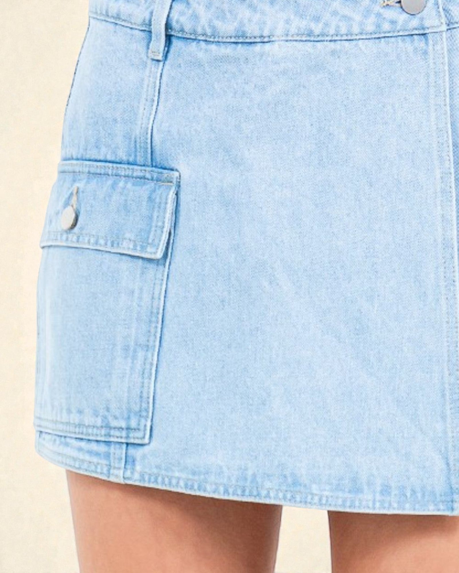 Light blue denim skirt with a pocket on a beige background
