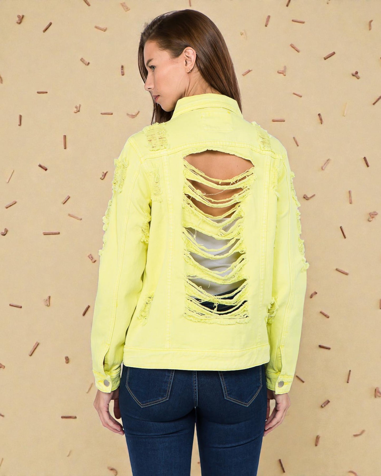 Woman wearing a neon yellow distressed jacket against a beige background