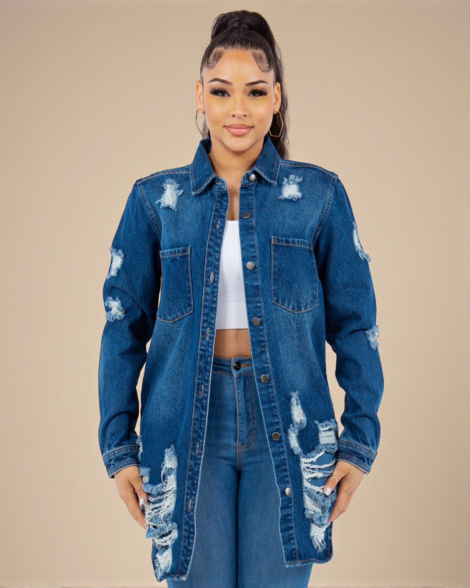 Woman wearing a distressed denim jacket and jeans on a beige background
