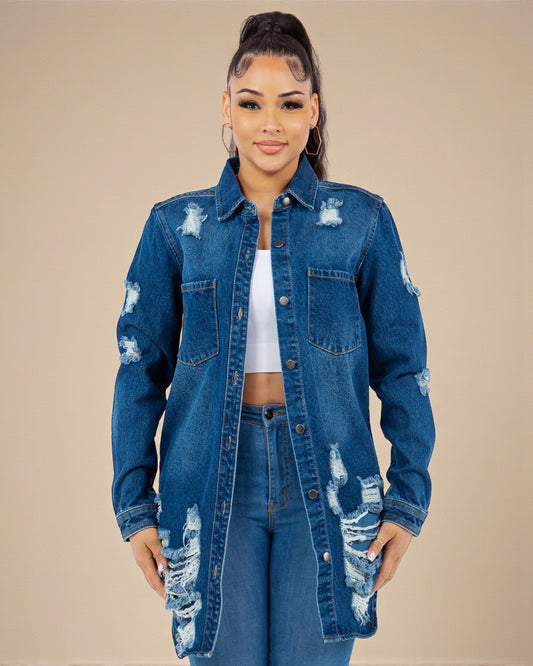 Woman wearing a distressed denim jacket and jeans on a beige background