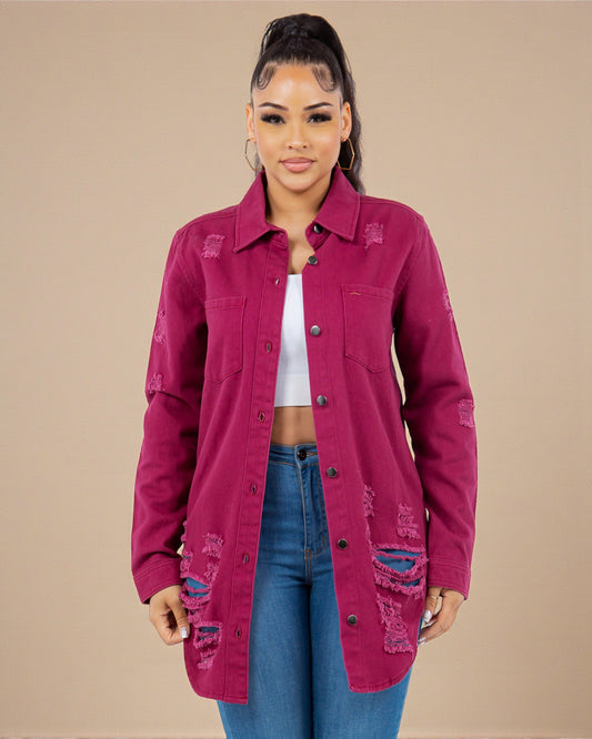 Woman wearing a distressed pink jacket over a white top and blue jeans on a beige background