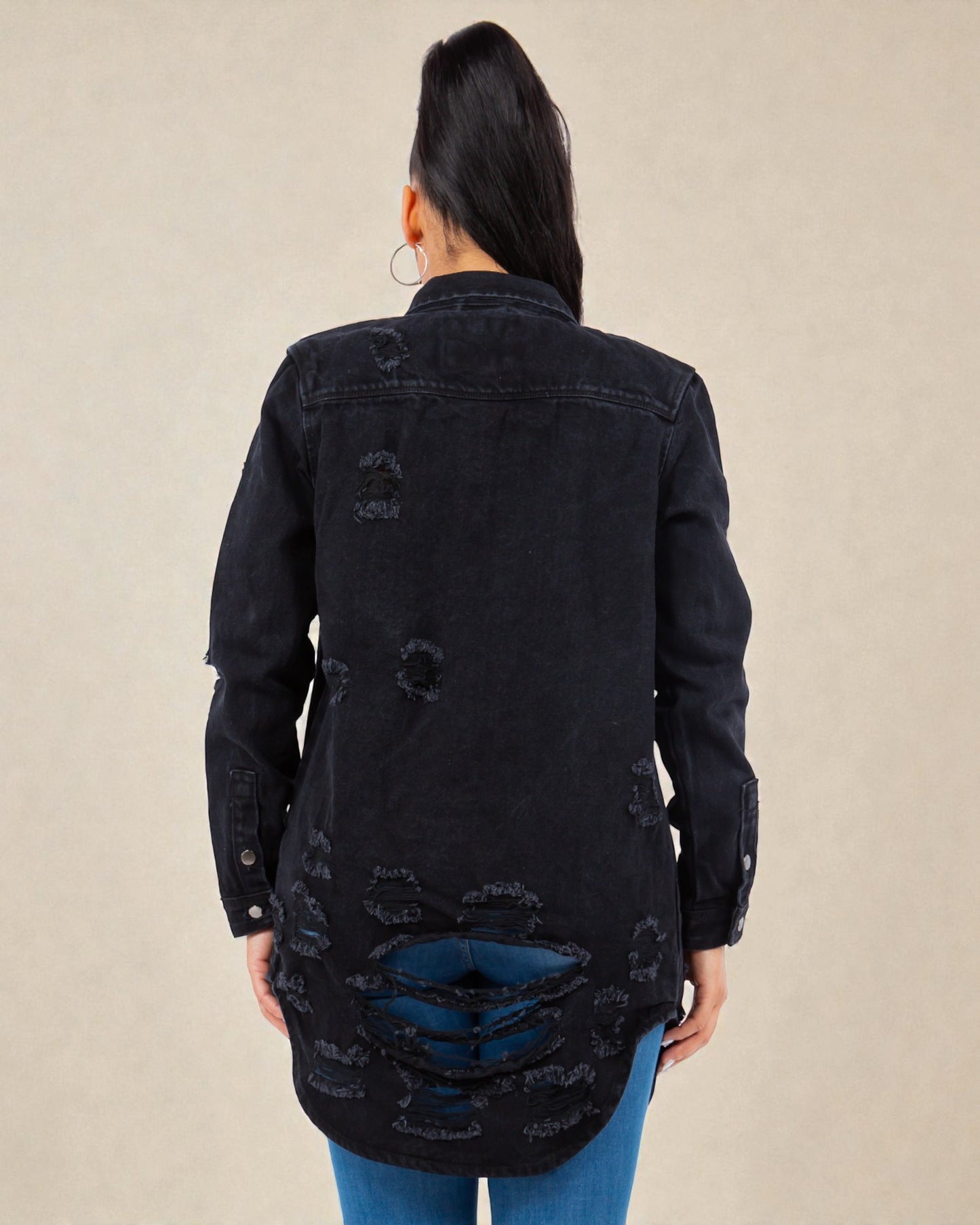 Black distressed denim jacket worn by a person on a beige background
