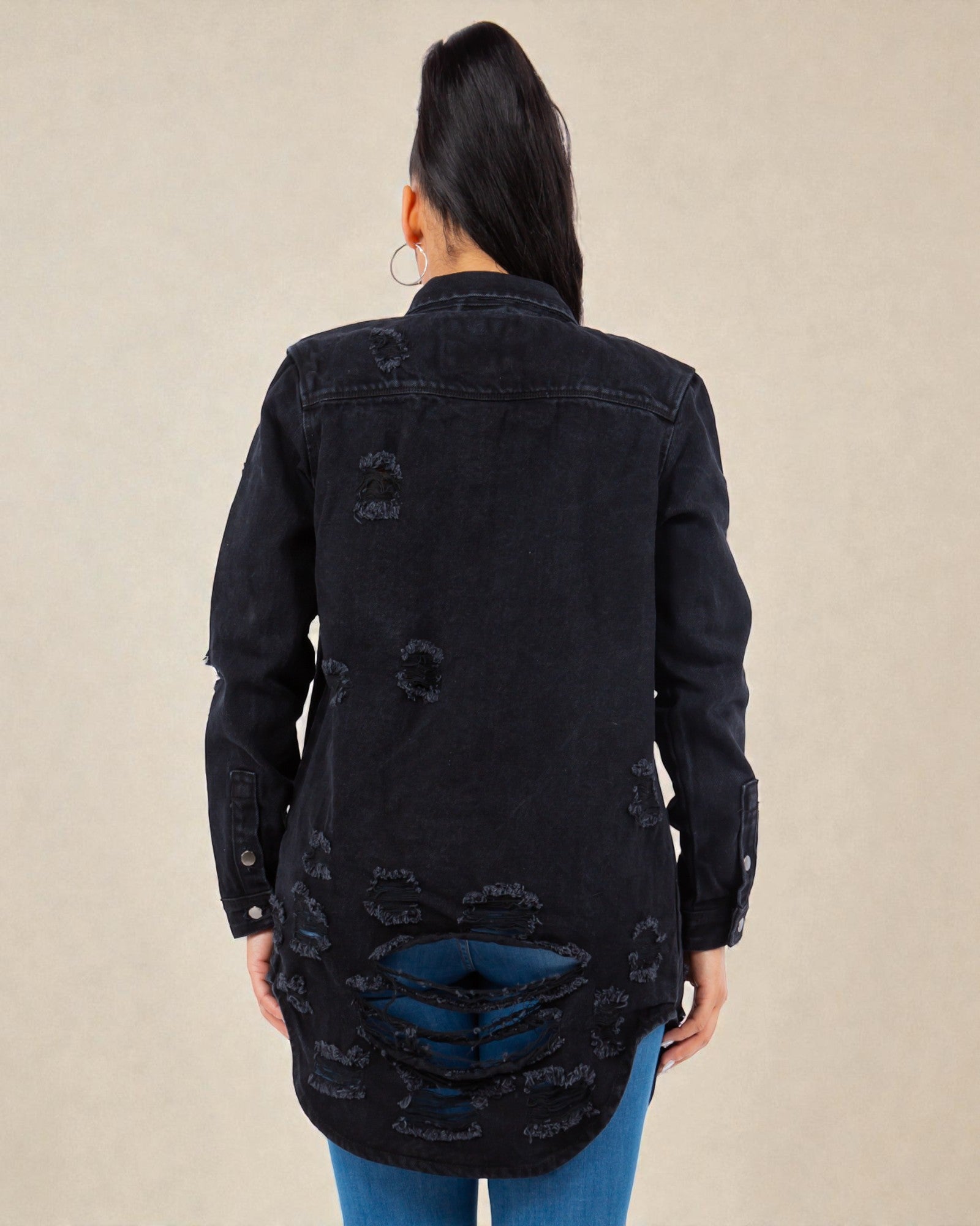 Black distressed denim jacket worn by a person on a beige background