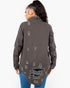 A woman shown from the back wearing a dark brown distressed button-up shirt jacket with ripped details, paired with blue jeans, against a plain white background.