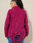 Person wearing a pink distressed denim jacket against a beige wall