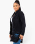 A woman modeling a black distressed denim shirt jacket with ripped details, worn over a white top and blue jeans, against a plain white background.