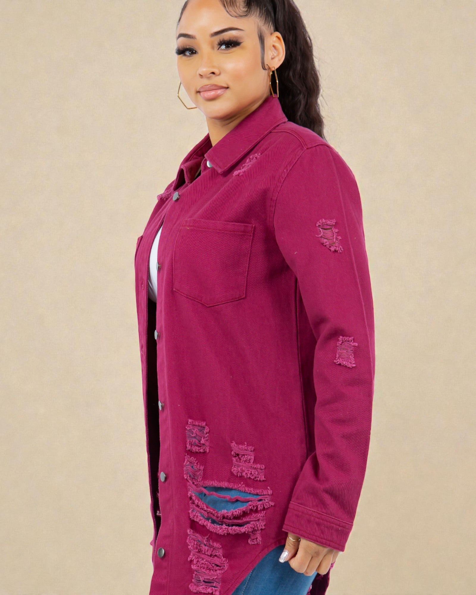 Woman wearing a burgundy distressed denim jacket on a beige background